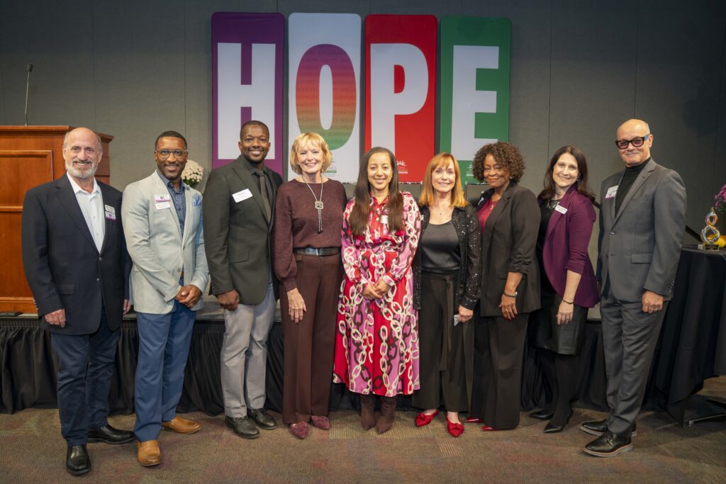 Board members standing together on a stage with a HOPE sign in the background.